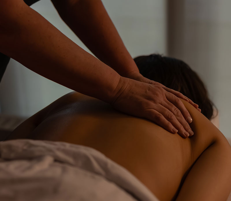Massage therapist massaging a patient's bare back.