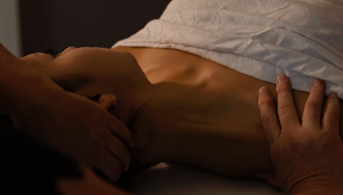 Massage therapist massaging a lying patient's shoulders.