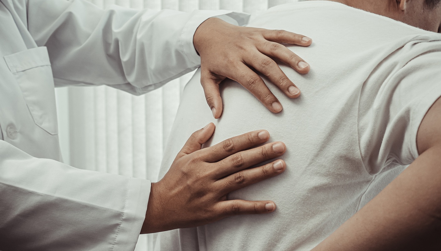 Doctor examines patient back in office.