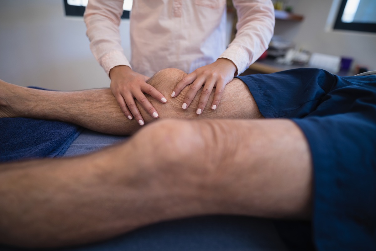 Female doctor massaging knee of patient
